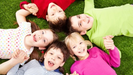Image of smiling young boys and girls playing on the grass